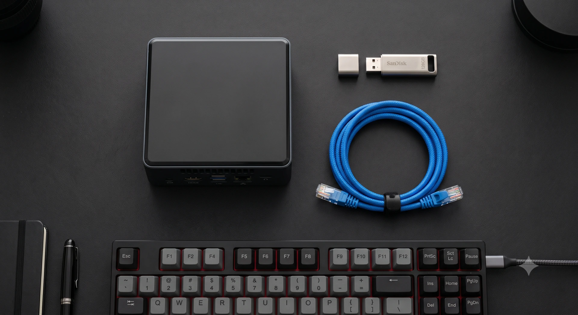Equipamentos para servidor caseiro incluindo pendrive, cabo de rede e mini PC organizados sobre uma mesa preta.